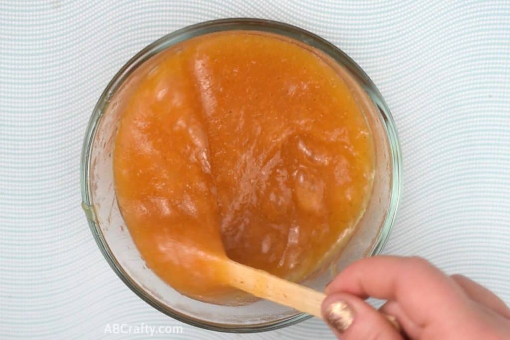 Stirring a sticky orange edible slime with a popsicle stick