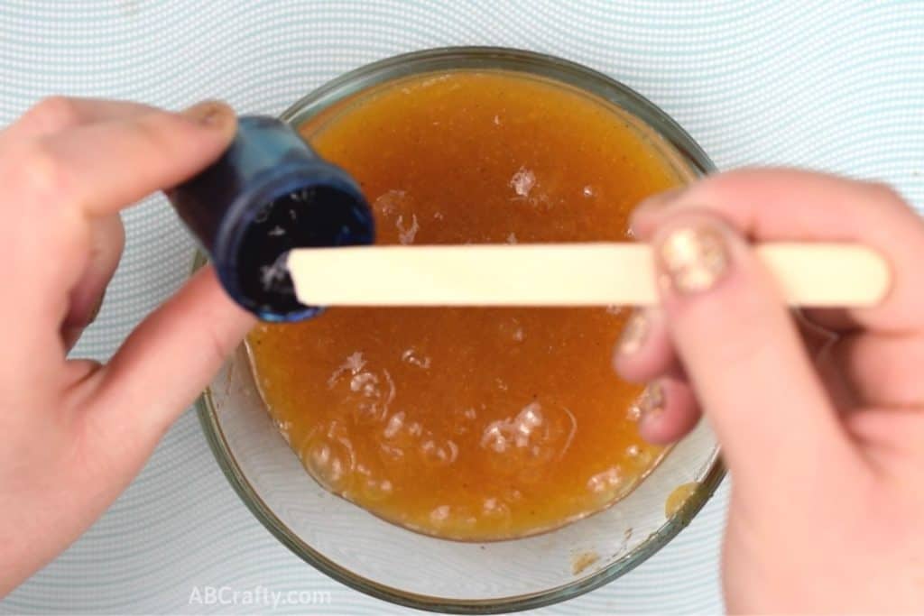 Scooping blue food dye out of the container with a popsicle stick