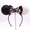 Finished diy cruella deville ears inspired by the disney movie 101 dalmatians and Cruella. One ear has black sequin fabric and the other white sequin fabric with a red minnie mouse bow with a white bow in front of it with black spots. The headband is covered in red sequin fabric.