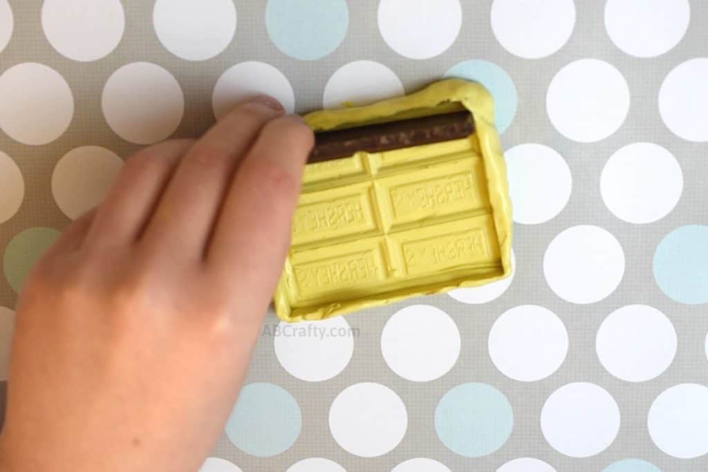 Removing broken chocolate from a yellow diy chocolate bar mold made from a hershey's bar