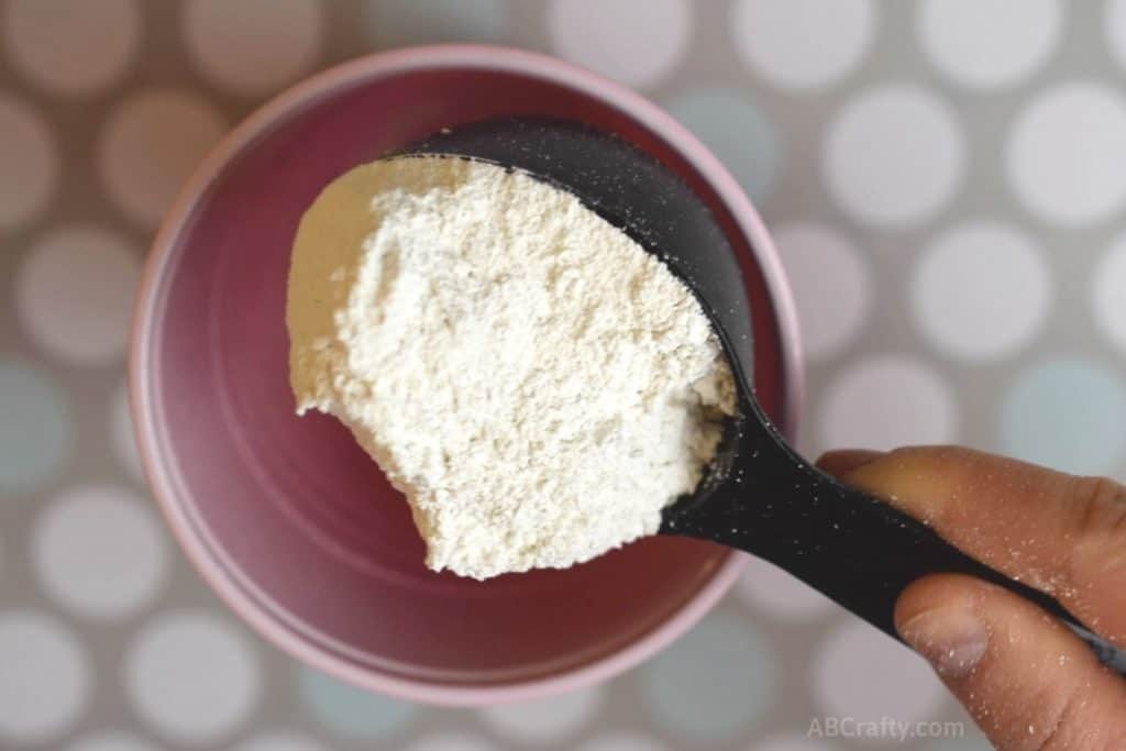 pouring plaster of paris from a black measuring cup into a red solo cup