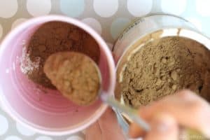 pouring cocoa powder from a spoon into a red solo cup