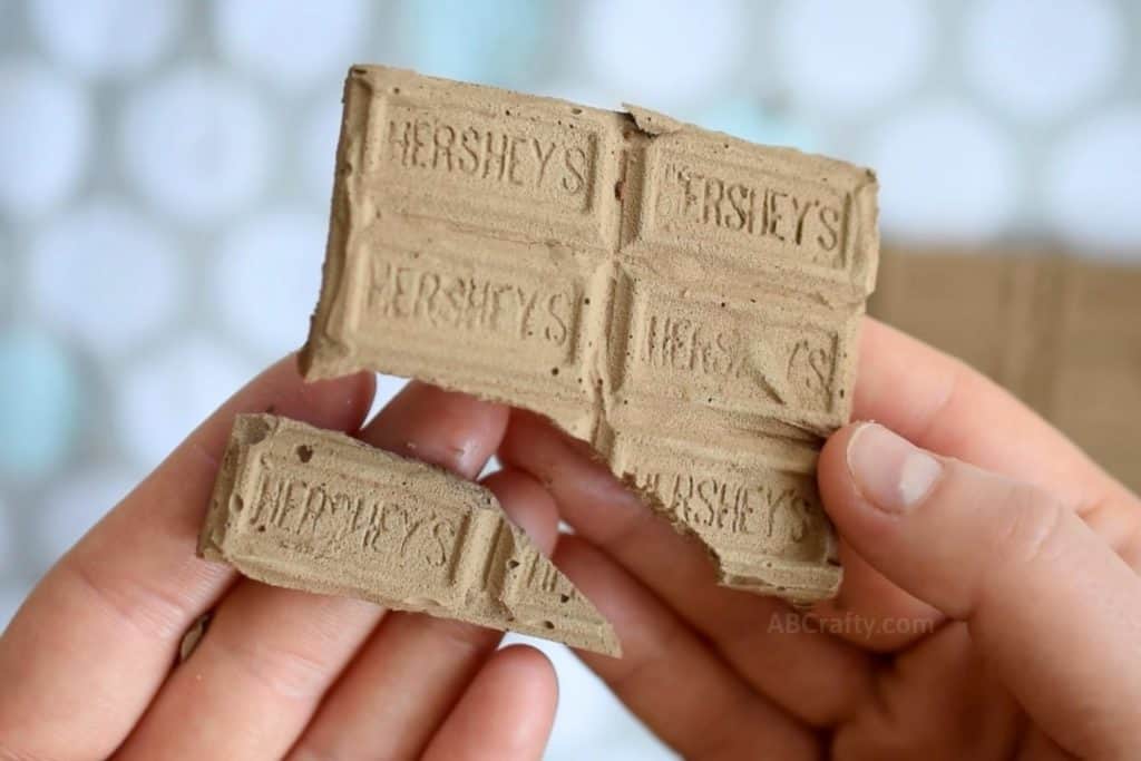 holding a broken chocolate bar chalk with one of the hershey bar segments broken off