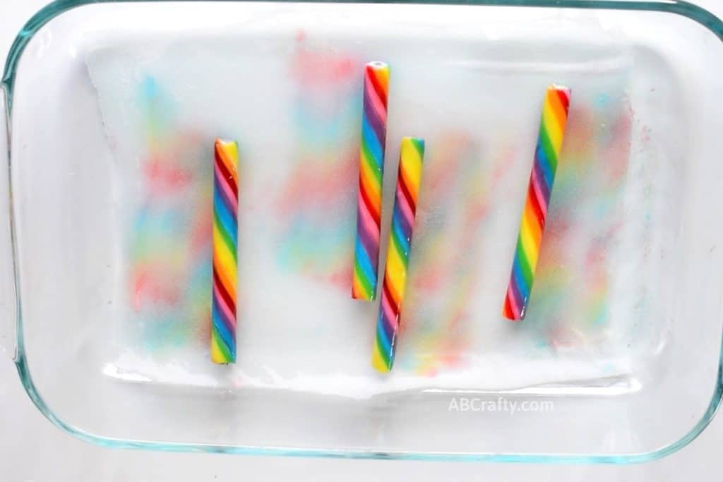 Rainbow stripes on fabric made from rainbow candy sticks releasing their food coloring