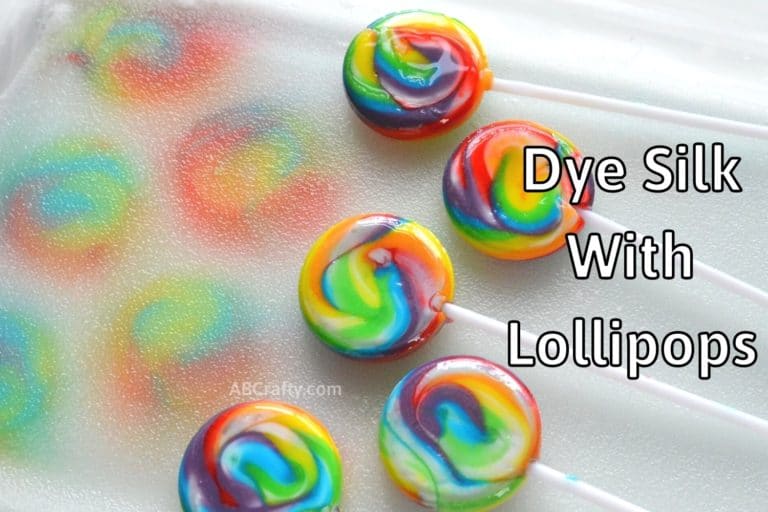 Multiple rainbow lollipops dyeing silk fabric underneath them, leaving rainbow circles on the silk. The title reads "dye silk with candy"