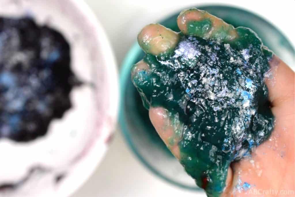 Holding homemade edible galaxy slime with glitter on top