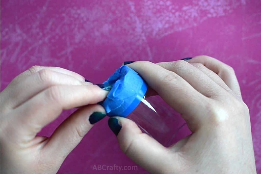 Taping the bottom of a shot glass with blue painters tape