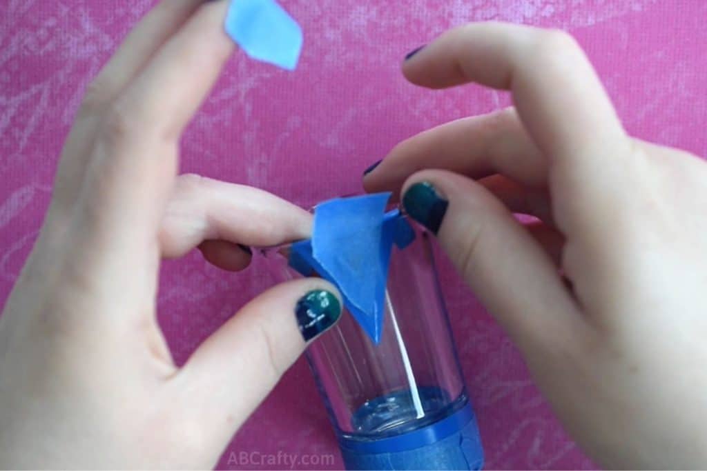 Taping a triangle at the top of a glass shot glass with blue painters tape