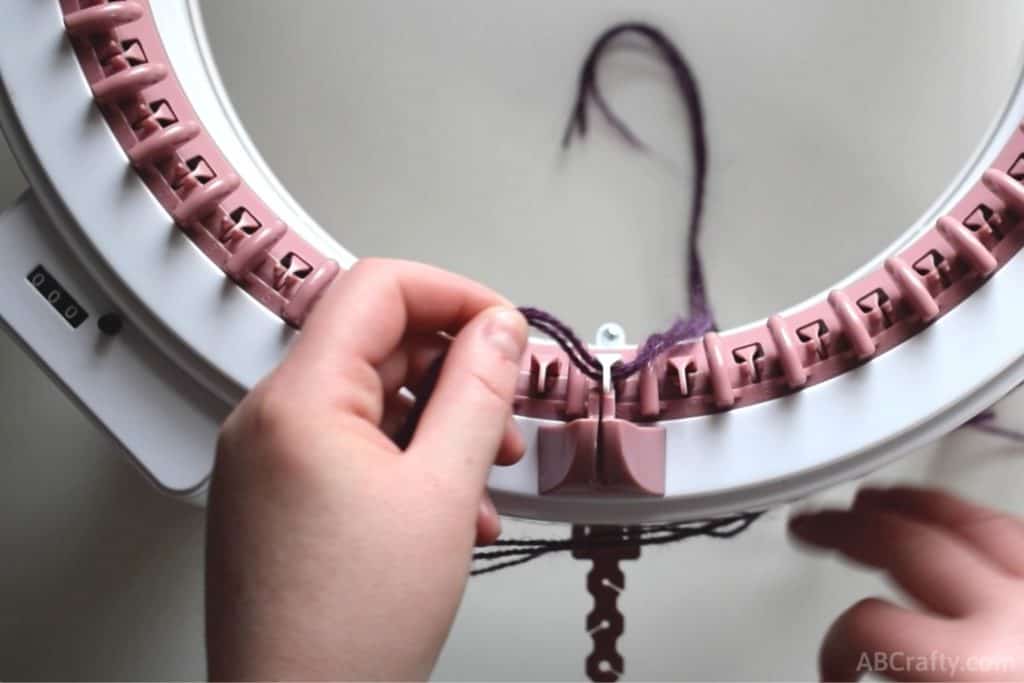 placing purple alpaca yarn around the white needle of a sentro knitting machine