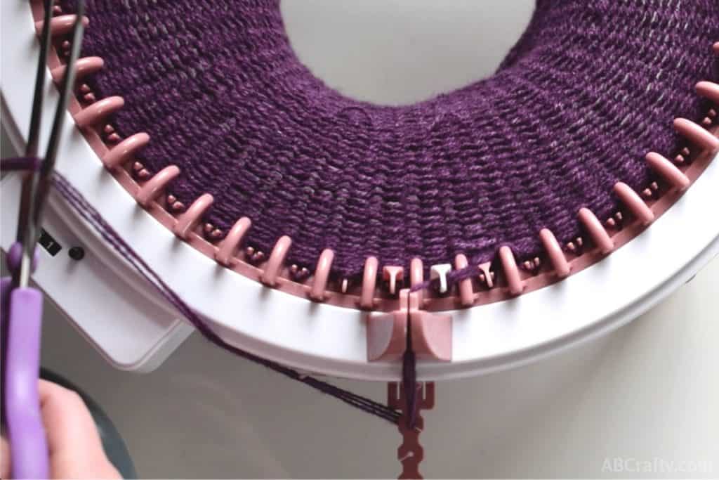 several rounds of purple alpaca yarn knit on the sentro knitting machine and cutting the yarn over the counter on the sentro knitting machine