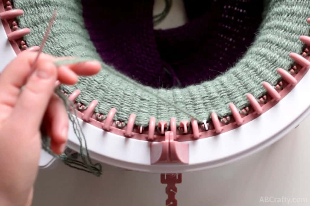 green yarn looped onto a pink plastic needle