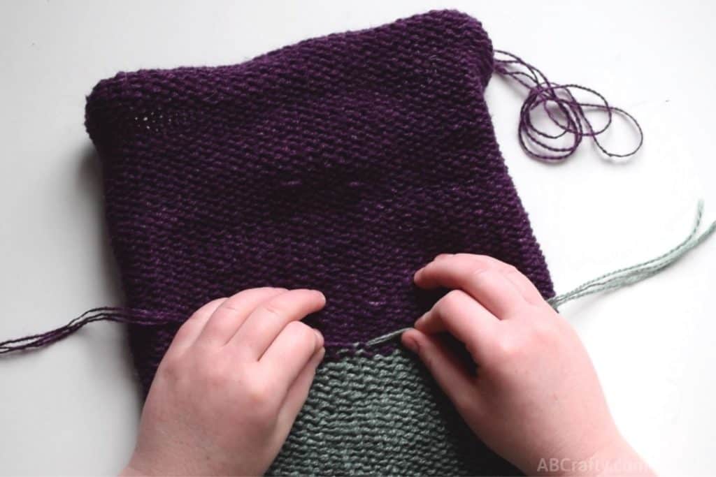 pulling the knot of purple and green yarns tight