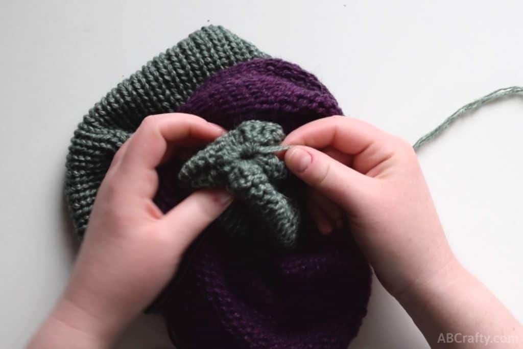 pulling the green side of the knit tube through the middle and part of the way out the purple and pulling the end of the green yarn to make the circle close