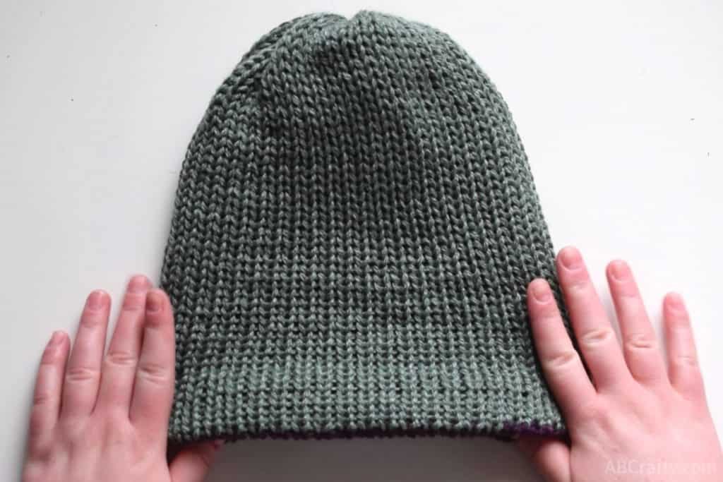 holding the handmade knit hat with the green side facing out