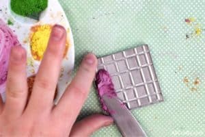 spreading a wet mixture of pink eyeshadow and rubbing alcohol into a clean eyeshadow tin