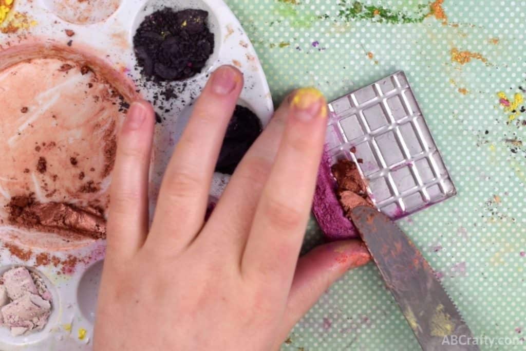 using a knife to put orange shimmer eyeshadow paste next to pink