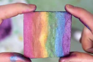 holding a finished diy rainbow highlighter that's in the shape of a square