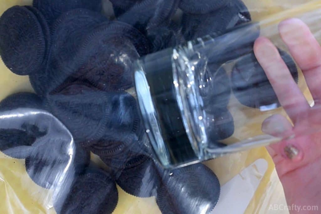 using a heavy glass to crush oreos in a plastic bag