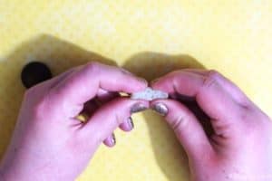 squishing a rope candy between the fingers to shape it into a mushroom stem