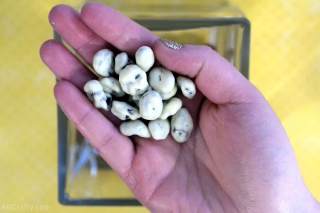holding a handful of yogurt covered raisins over a square glass container