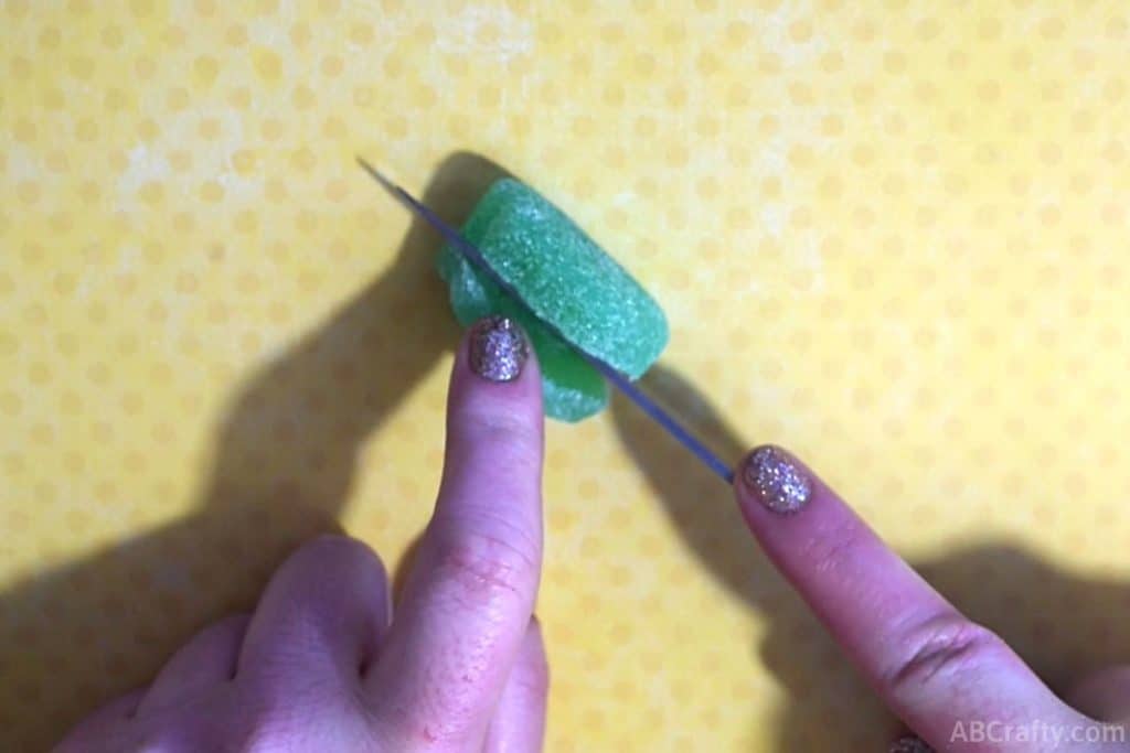 using a knife to cut off one third of a green mint leaf gummy