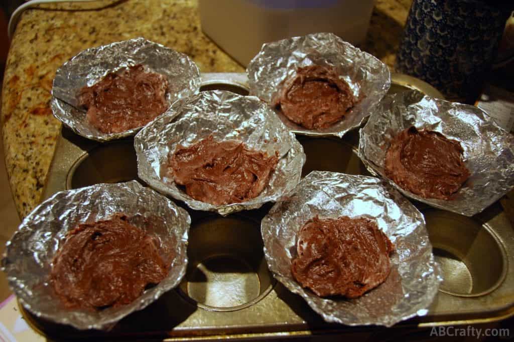 chocolate batter inside cones made of tin foil in a cupcake tin