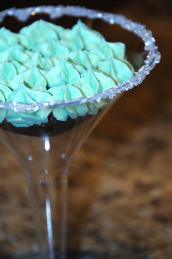 photo of half of a martini glass with a chocolate cupcake and green bailey's frosting with sugar on the rim