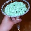 hand holding a martini glass with sugar on the rim and green bailey's buttercream frosting on a cupcake inside the martini glass