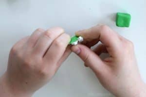mixing a small amount of green clay with white clay with a green clay cube in the corner