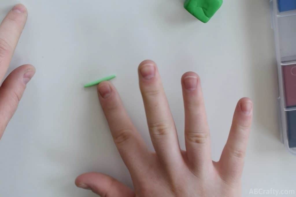 rolling a small green log of clay with an index finger