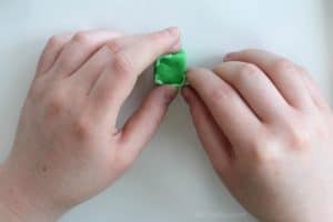 adding small strips of light green eraser clay to the corners of a green cube