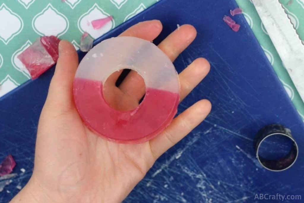 holding a round soap that is half red and half white with the center cut out