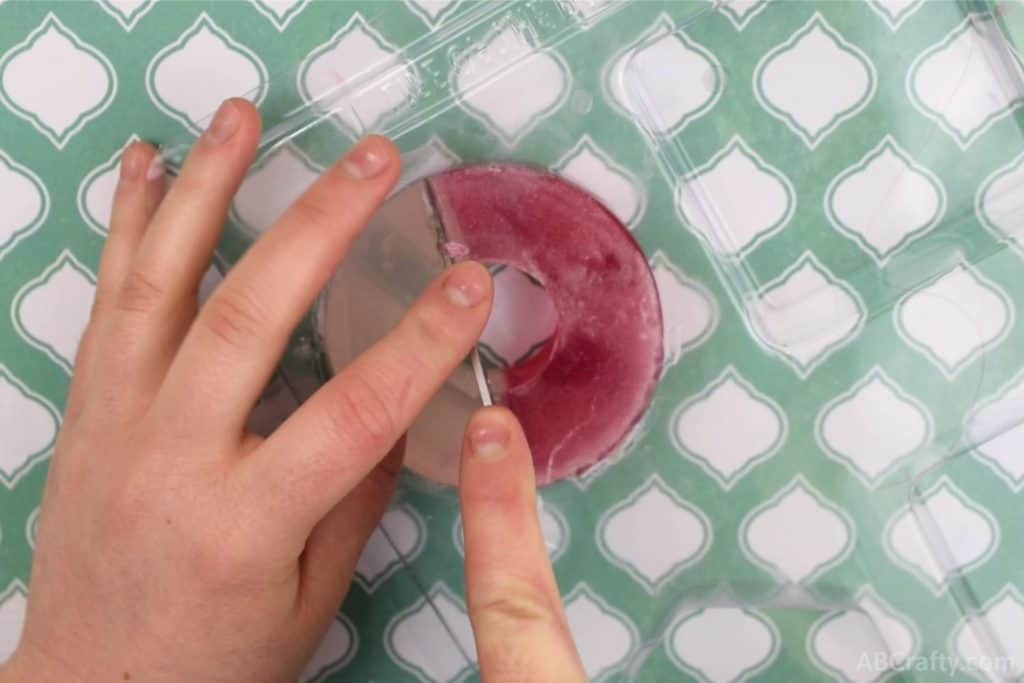 cutting into a red and white round soap with the center cut out, resembling a donut