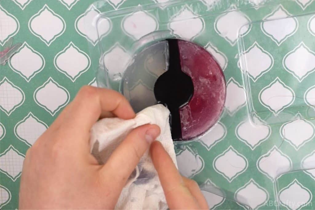 using a paper towel to wipe excess soap while making a pokeball soap