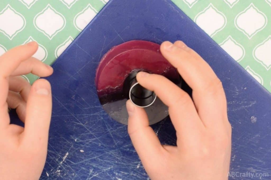 Using a circle cookie cutter to cut out the center button of a pokeball soap