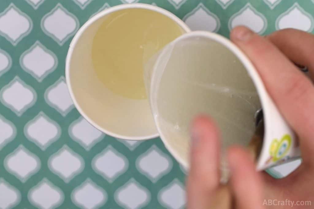 pouring melted clear glycerin soap from one paper cup into another