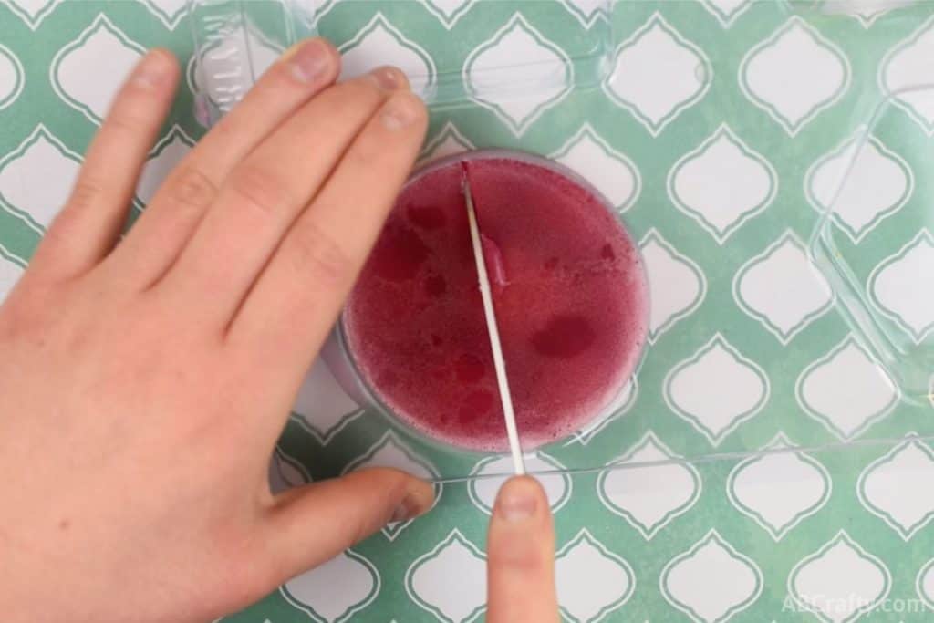 using a knife to cut a round red soap in half