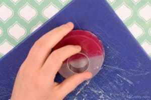 holding a small circle cookie cutter on top of a round soap that is half red and half white