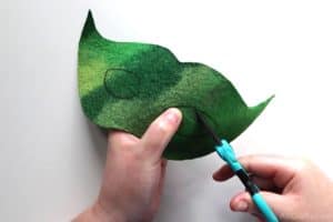 cutting the eye hole out of a green felt mask