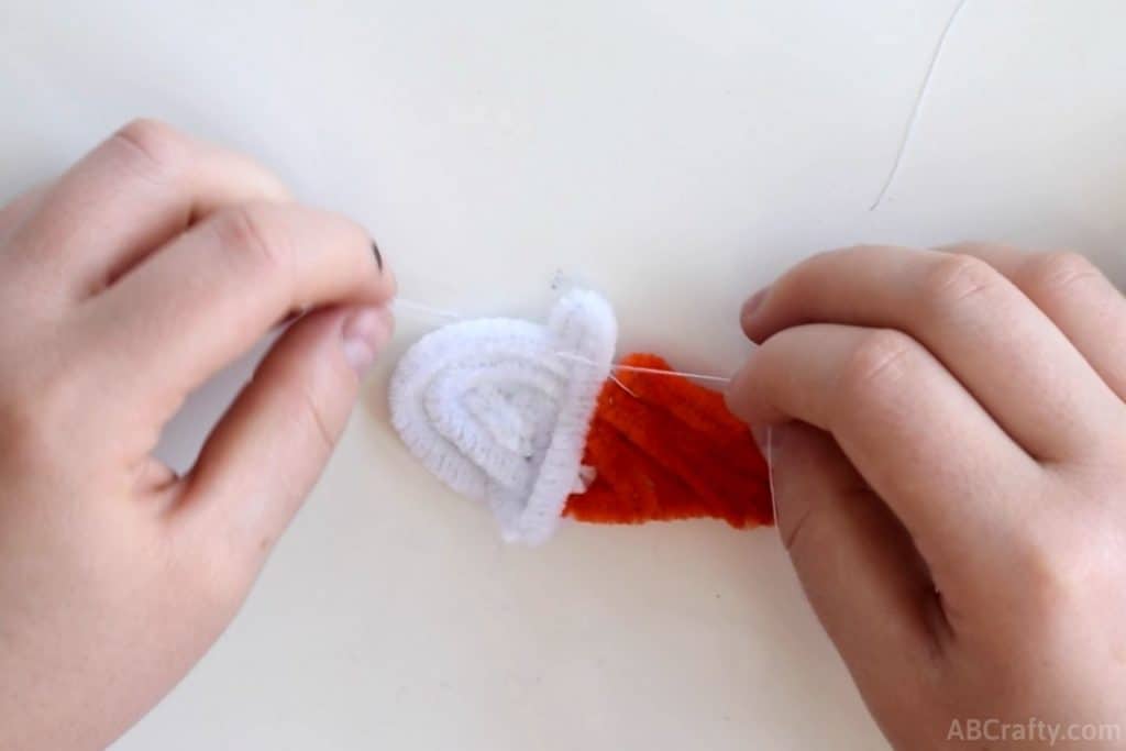 using white thread the top of a scoop of ice cream made of pipe cleaners to the cone