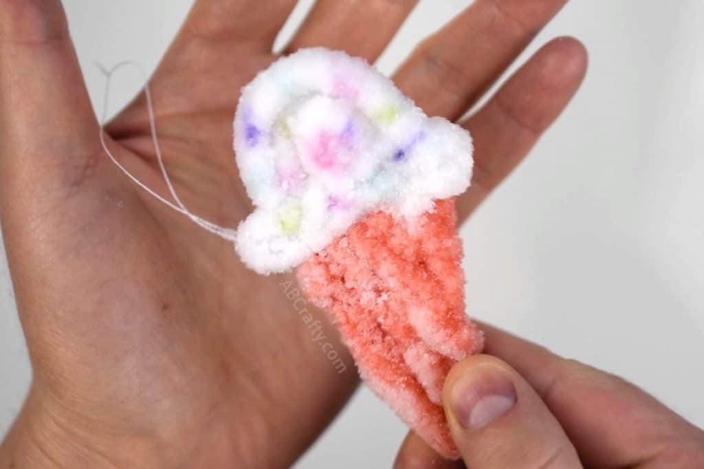 holding an ice cream cone crystal ornament that has multi colored sprinkles on the ice cream