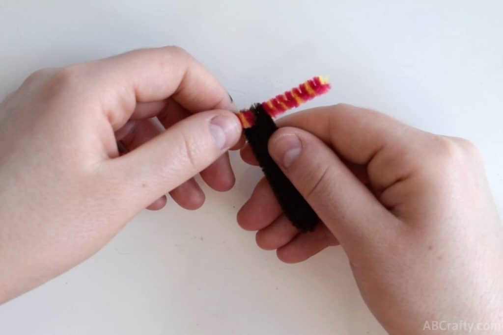 bending the end of the brown pipe cleaner or chenille stem over the colorful pipe cleaner