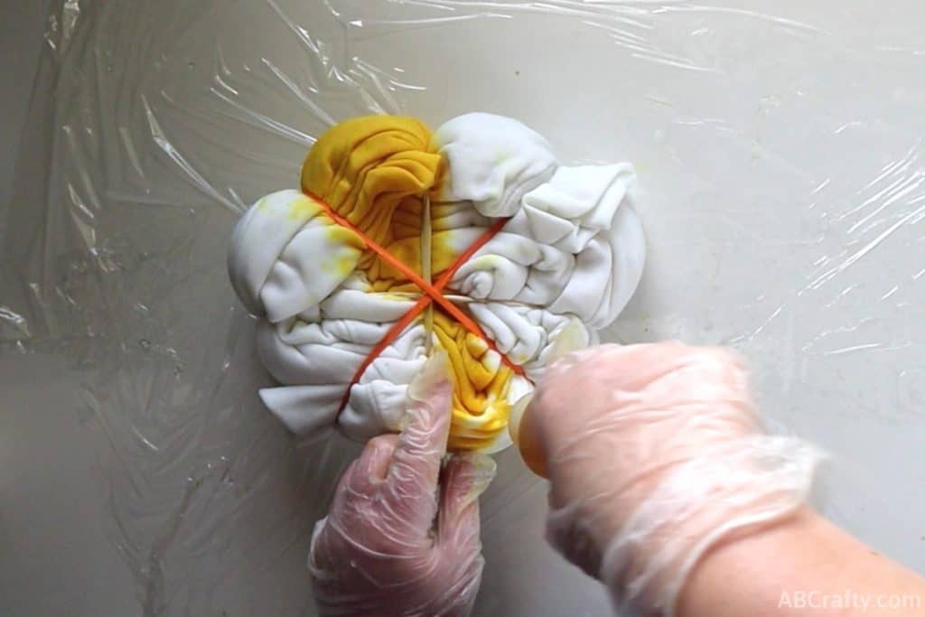 pouring yellow dye into the opposite section of a white sweatshirt
