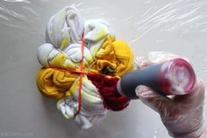 pouring red tie dye into a section between rubber bands