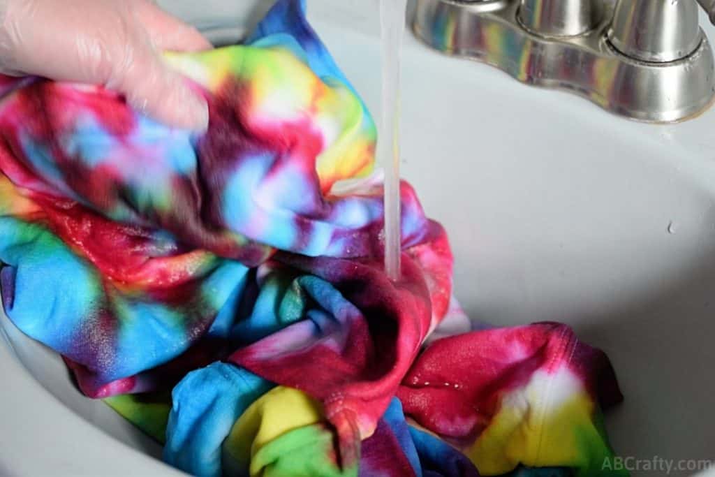 washing a rainbow tie dye sweatshirt under water