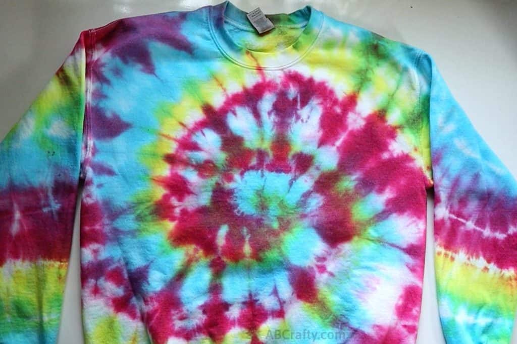 rainbow tie dye sweatshirt on a table with a spiral tie dye pattern