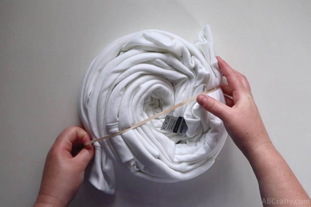 wrapping a rubber band around a white sweatshirt that's been wrapped into a spiral