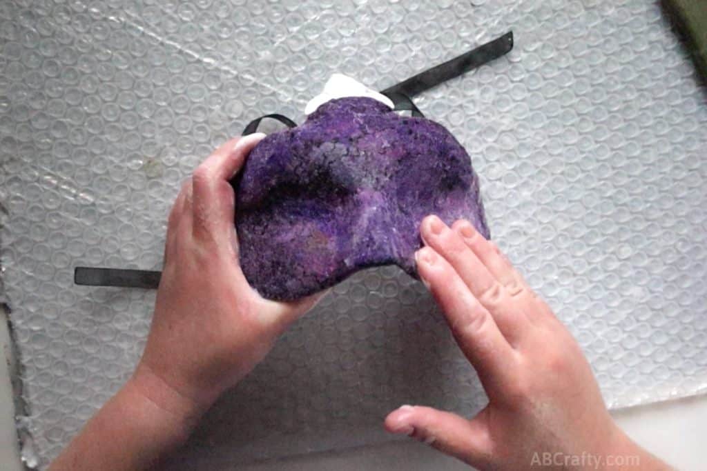 purple wool getting felted on top of a form and taking the shape of a masquerade mask