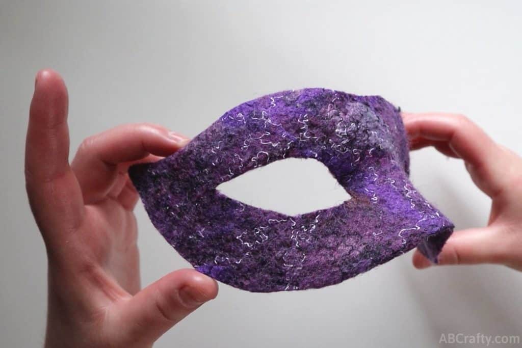showing the side of a purple wet felted Venetian mask showing it's holding its shape