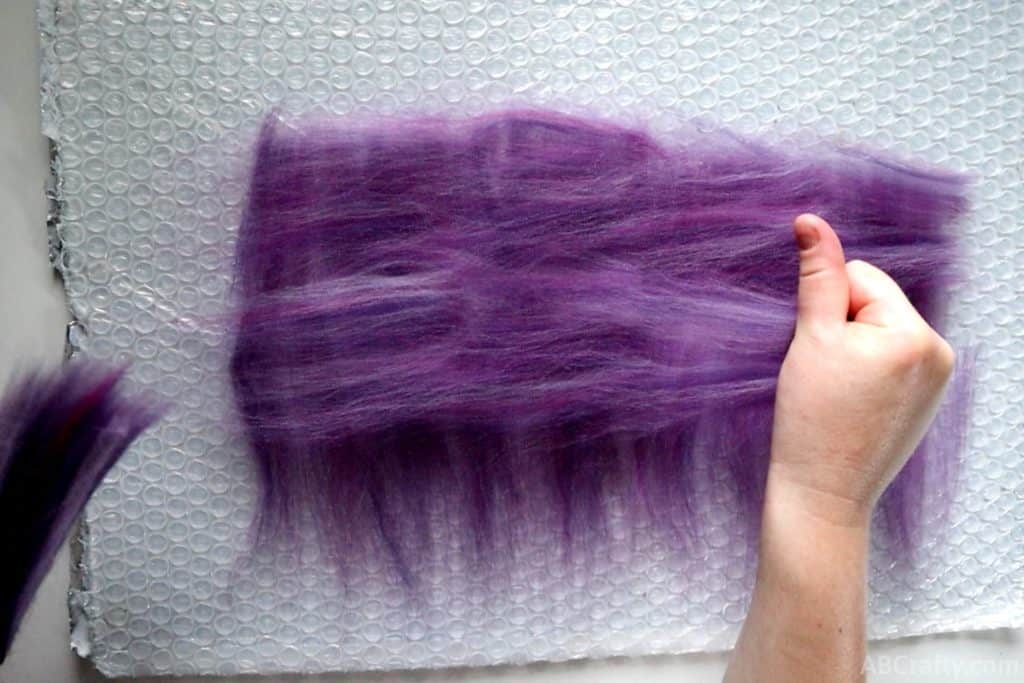 laying out purple wool fibers into perpendicular layers